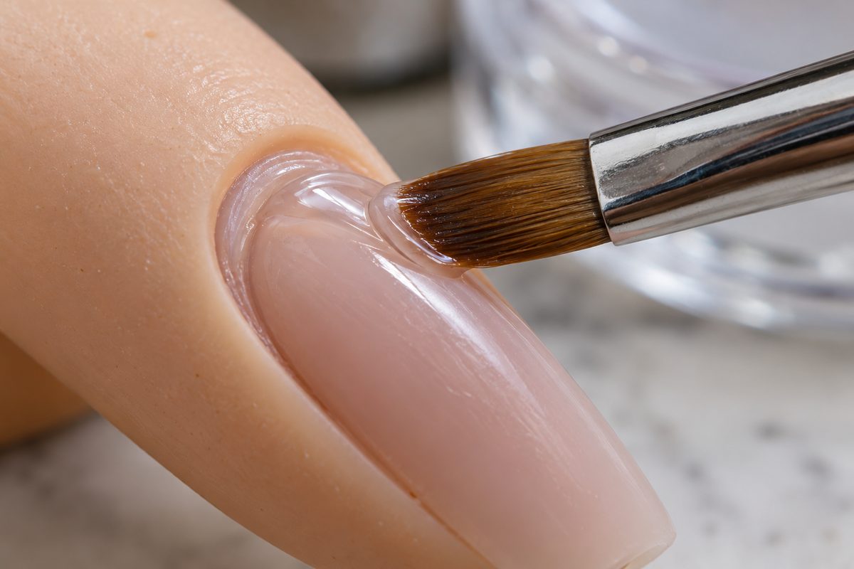 Synthetic flat oval brush controlling a gel bead near a nail cuticle edge